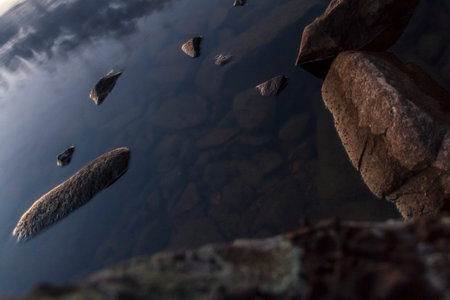 Small stones in the water of a lake in the early morning.の写真素材