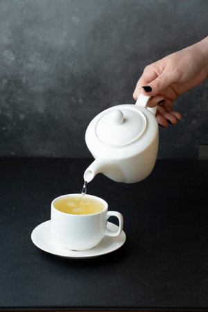 Pouring tea from teapot into cup on table, closeupの写真素材