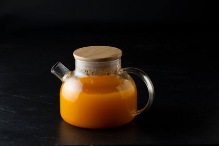 Fresh orange juice in a glass teapot on black background.の写真素材