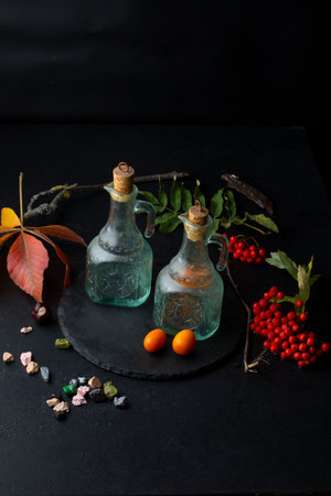 Autumn still life with bottles and rowan berries on black backgroundの写真素材
