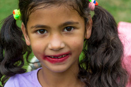 Little gypsy girl with smudged lipstick makeup tried to be pretty model fashionの写真素材