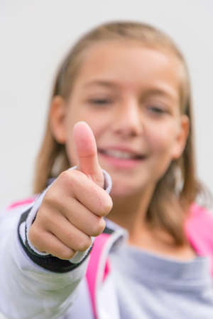 Young girl gesticulating thumbs up in front of face out of focusの写真素材