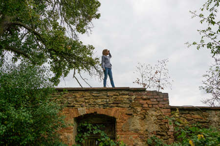Young girl child stay on ancient old wall looking aroundの写真素材