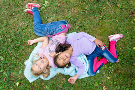 Sick invalid girls children lay together in garden play and smileの写真素材
