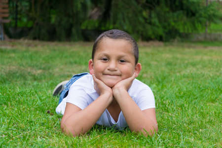 Happy little gypsy child boy lay in grass smilingの写真素材
