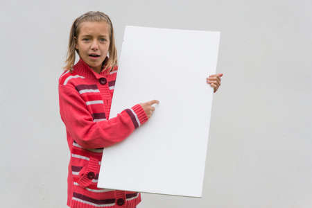 Dissatisfied child girl presenting empty white bannerの写真素材