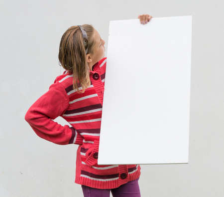 Child girl study interesting blank poster holding it in handsの写真素材