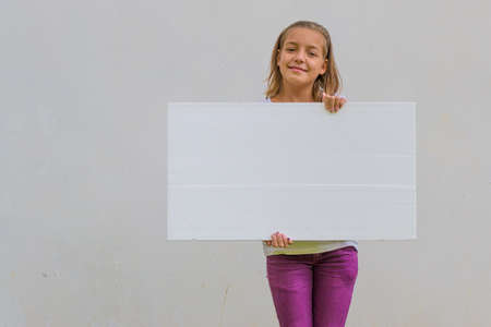 Happy smiling child girl presenting empty bannerの写真素材