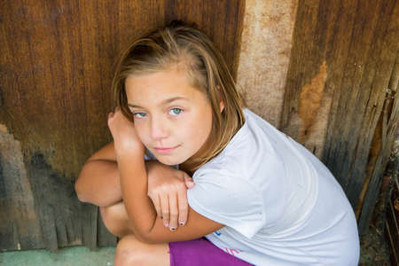 Sad child girl victim of bullying violence or abuse sitting unhappy and alone looking directly up