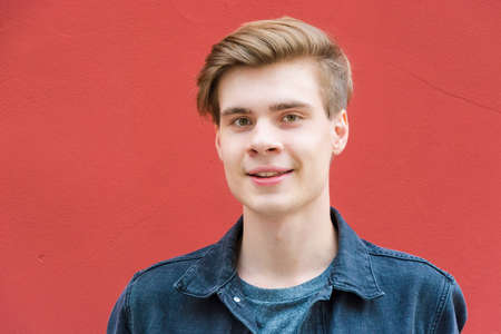 Happy smiling teenager boy portrait smiling face over red background wall contrastの写真素材
