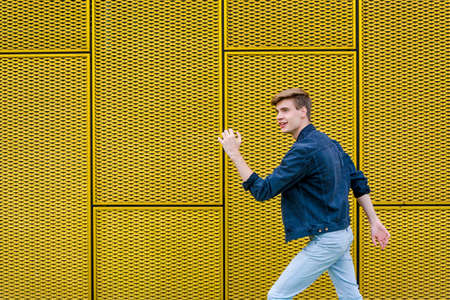 Teenager boy walking happy and fast with smile over yellow contrasting background with copyspaceの写真素材