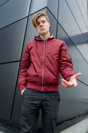 Teenager boy expressing question and doubt standing in front of black urban background outdoor...