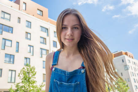 Happy smiling teenage girl with long hair in summer city hotel areaの写真素材