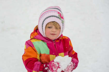 Little child holding snow in winterの写真素材