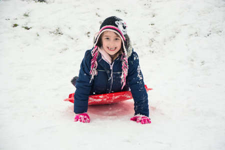 Happy smiling little child on snow in winter playing on hill