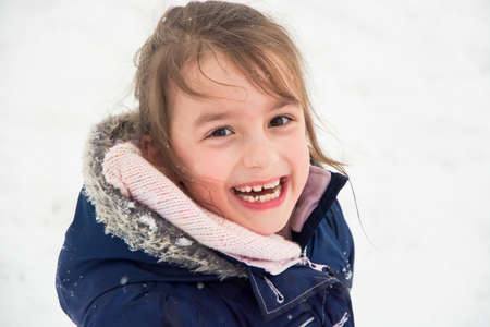 Happy child closeup portrait of girl enjoing winter and snow