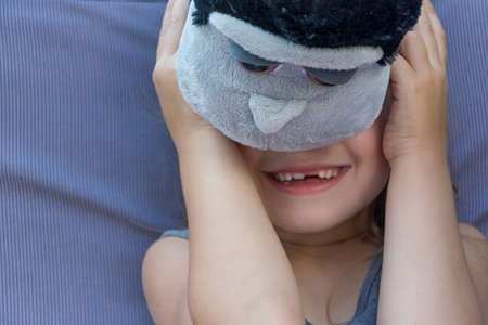 Happy shy child girl hiding her face behind the furry toy smilingの写真素材