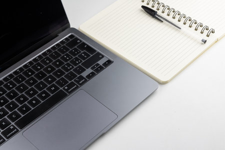 Laptop with notebook and pen on white background, business concept.