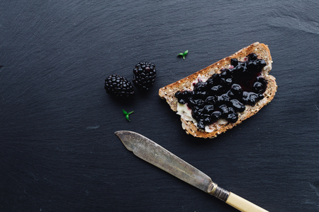 Healthy breakfast with blue berry jam with toast on black slate background viewed from topの写真素材