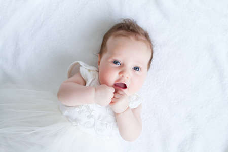 Blue eyed baby girl in a white dress の写真素材