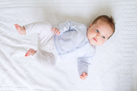 Newborn in white and blue on a white blanket の写真素材