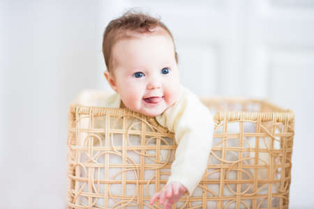 Beautiful little baby smiling out of a wicker basket 
