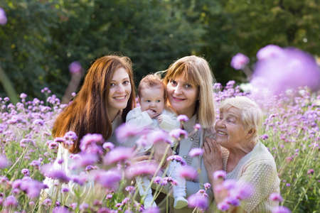 Four generations of beautiful women standing in a colorful lavender field の写真素材