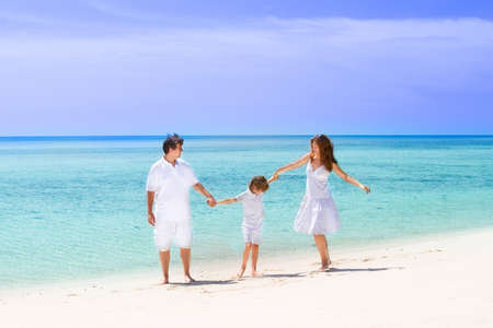 Beautiful family of three dancing on a tropical beach の写真素材