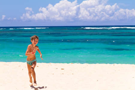 Boy running on a tropical beach with turquoise water の写真素材