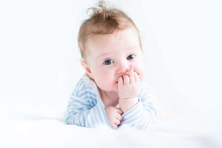 Sweet baby in a blue shirt sucking on its finger 