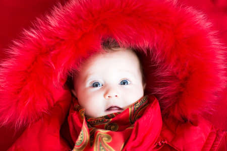 Little baby girl in a red fur jacket の写真素材