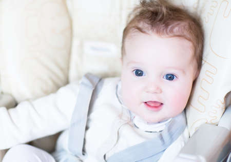 Sweet baby girl sitting in a high chair and waiting for lunch 
