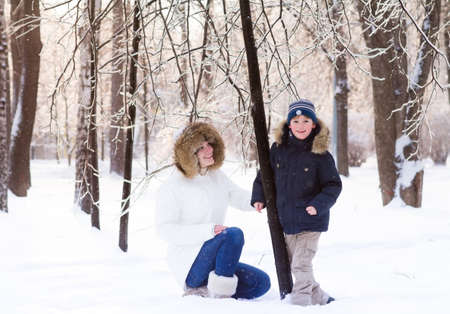 Mother and child playing in deep snow on sunset の写真素材