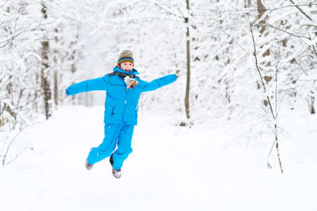Funny boy jumping in a snowy park の写真素材