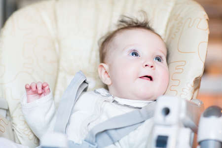 Sweet baby girl waiting for dinner in a high chair 