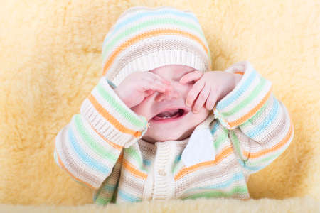 Very tired sleepy baby sitting in a warm sheepskin stroller foot muff 