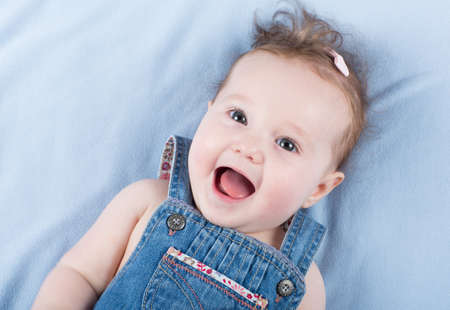 Laughing happy baby girl wearing a jeans dress の写真素材