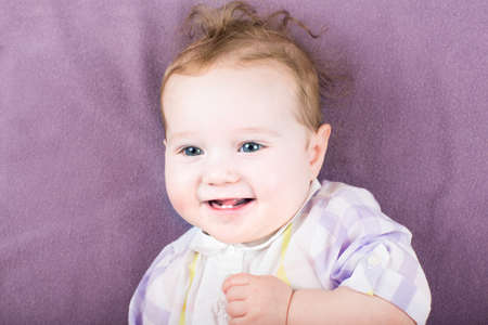 Sweet baby girl in a purple dress on purple background の写真素材
