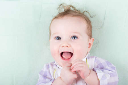 Adorable baby girl with funny curly hair laughing happily の写真素材