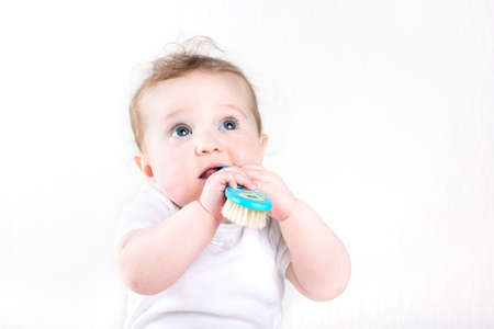 Funny little baby playing with a hair brush の写真素材