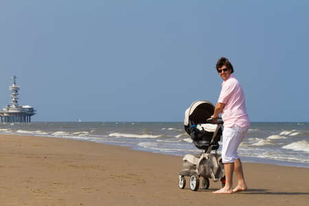Young father walking with a baby stroller on a beach の写真素材
