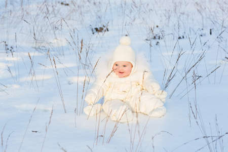 Little baby playing in a snowy winter field の写真素材