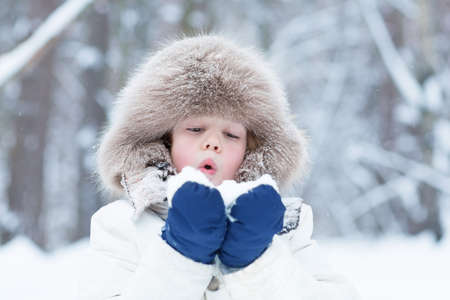 Cute child playing with snow in a winter park の写真素材