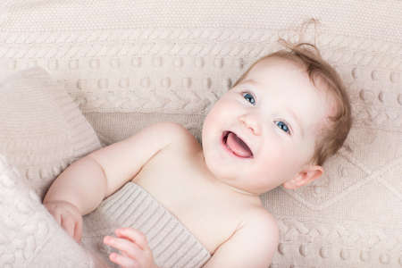 Funny laughing baby under a knitted blanket の写真素材
