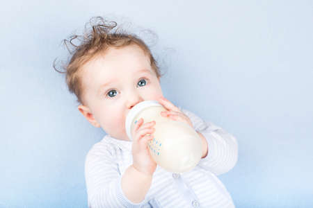 Cute baby with a milk bottle on a blue blanket の写真素材