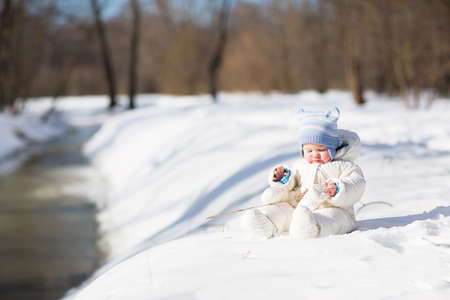 Funny baby playing at a snowy river の写真素材
