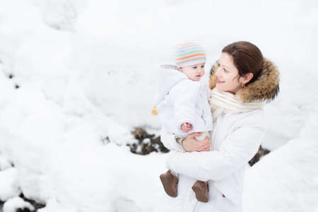 Mother and baby walking in a snowy park の写真素材