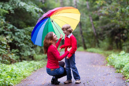 Mother and son laughing under a colorful umbrella の写真素材