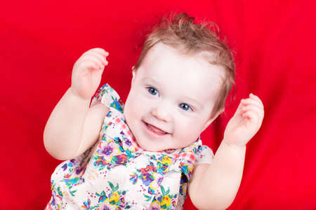 Funny baby girl playing on a red blanket の写真素材
