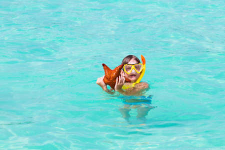 Little boy playing with a star fish on a tropical beach の写真素材
